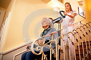 Nurse using machine for climbing to the stairs and helps old mat