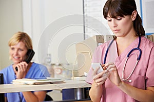 Nurse Using Mobile Phone At Nurses Station