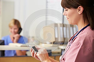 Nurse Using Mobile Phone At Nurses Station