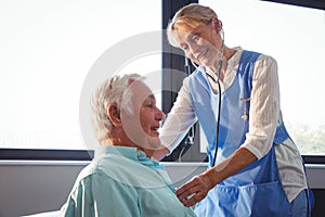 Nurse using stethoscope to take care of a senior man