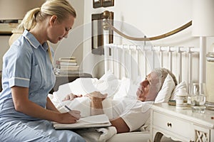 Nurse Visiting Senior Male Patient In Bed At Home