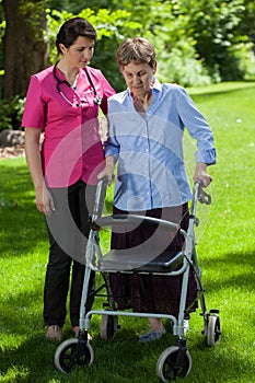 Nurse walking beside woman with orthopedic walker