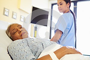 Nurse Watching Sleeping Senior Woman Patient In Hospital