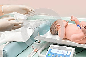 A nurse weighs on the scales of a newborn baby