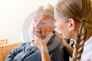 Nurse wiping mouth of senior woman in nursing home