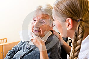 Nurse wiping mouth of senior woman in nursing home photo