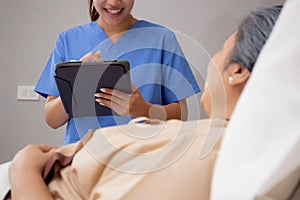 Nurse writing report document about medical and health care on tablet while explaining and check and diagnostic.