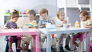 Nursery babies eating food. Kids have lunch in daycare