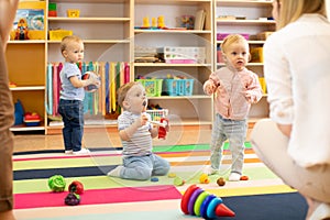 Nursery babies play on floor with carers or mothers in day care centre