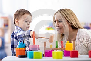Nursery baby and caregiver play with montessori toys at table in daycare centre photo