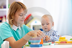 Nursery baby playing with teacher in the classroom