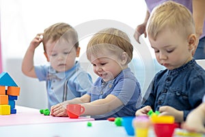 Nursery kids playing with play clay at kindergarten or playschool photo