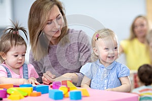 Nursery children playing with teacher in the classroom