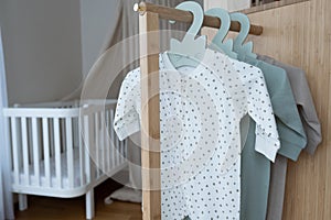 Nursery interior. Set of cute bodysuits for newborn on hangers. Copy space. The concept of baby clothes, motherhood