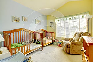 Nursery room with two cribs for twins and lots of toys.