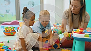 Nursery school. Toddlers and their teacher playing with colorful plastic playhouses, cars and boats. Imagination