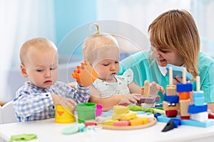 Nursery teacher and cute babies playing in creche