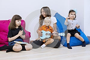 Nursery teacher helps a little boy to play the guitar
