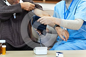 Nurses or caregivers take care of elderly by helping to check their blood pressure