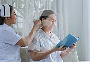 Nurses combing hair for elderly to Care and elderly read book. Caregiver with elderly of kindness concept