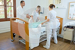 Nurses lifting patient under doctor`s supervision