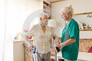 Nursing assistant helping senior woman with walking frame photo