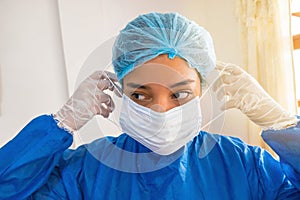 Nursing assistant protects herself against infections, using a mask to fight Coronavirus. Global epidemic that affects large