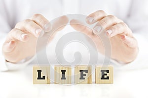 Nurturing hands of a man cupped over the word Life photo