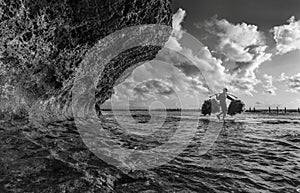 Indonesian farmer carrying seaweed collected from his sea farm to house for drying in morning, Nusa Penida, Indonesia