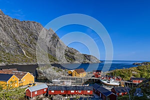 Nusfjord fishing village in Lofoten, Norway, presents a picturesque ensemble of traditional red and yellow wooden Rorbu