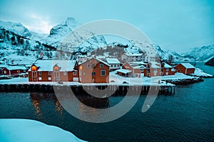 Nusfjord, small fishing village in Norway, during amazing winter evening, ships, snow and yellow cabins.