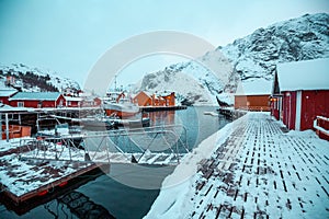 Nusfjord, small fishing village in Norway, lofoten, during winter, ships, snow and yellow cabins.