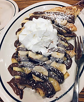nutella, chocolate crepes with banana slices, whipped cream