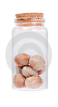 Nutmeg in a glass bottle with cork stopper, isolated on white. photo
