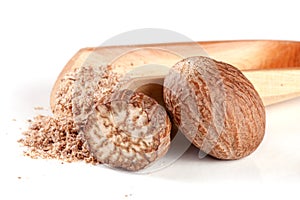 Nutmeg and half with powder in a scoop on white background