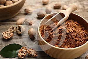Nutmeg powder and seeds with green leaf on table