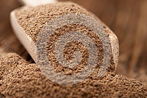 Nutmeg powder in a wooden scoop close up