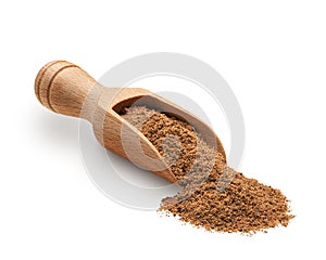 Nutmeg powder in a wooden scoop isolated on white
