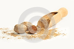 Nutmegs and nutmeg powdered on a wooden scoop on a white background