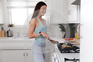 Nutrition, healthy eating and fitness portrait of an asian female cooking vegetables in the kitchen in active sportswear, commerci