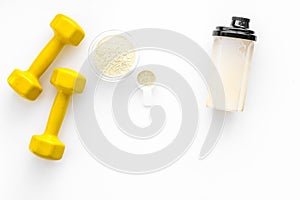 Nutrition for muscle growth. Scoop of protein near shaker and dumbbell on white background top view copy space