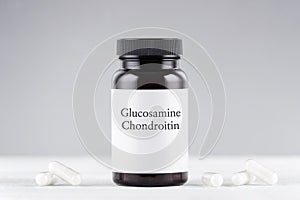 Nutritional supplement glucosamine and chondroitin bottle and capsules on gray