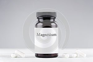 Nutritional supplement magnesium bottle and capsules on gray