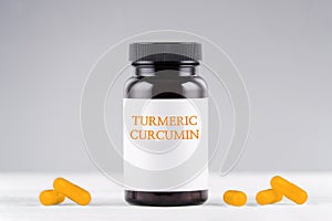 Nutritional supplement turmeric curcumin bottle and capsules on gray