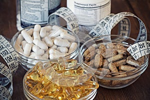 Nutritional supplements in capsules and tablets, on wooden background