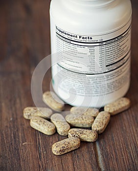 Nutritional supplements in capsules and tablets, on wooden background