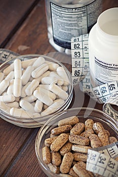 Nutritional supplements in capsules and tablets, on wooden background