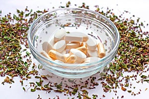 Nutritional supplements pills in a bowl on dried herbs background. Alternative herbal medicine, naturopathy and homeopathy