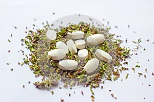 Nutritional supplements pills on dried herbs background. Alternative herbal medicine, naturopathy and homeopathy concept