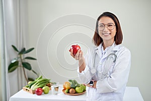 Nutritionist desk with healthy fruits, juice and measuring tape. Dietitian working on diet plan at office, smiling at camera.